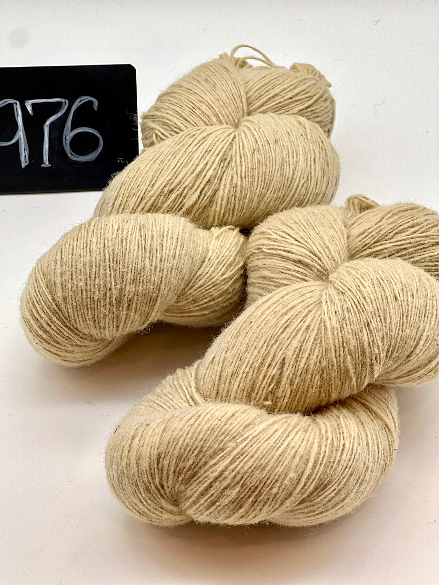 Three skeins of beige yarn on a white background with a black sign displaying '176'.