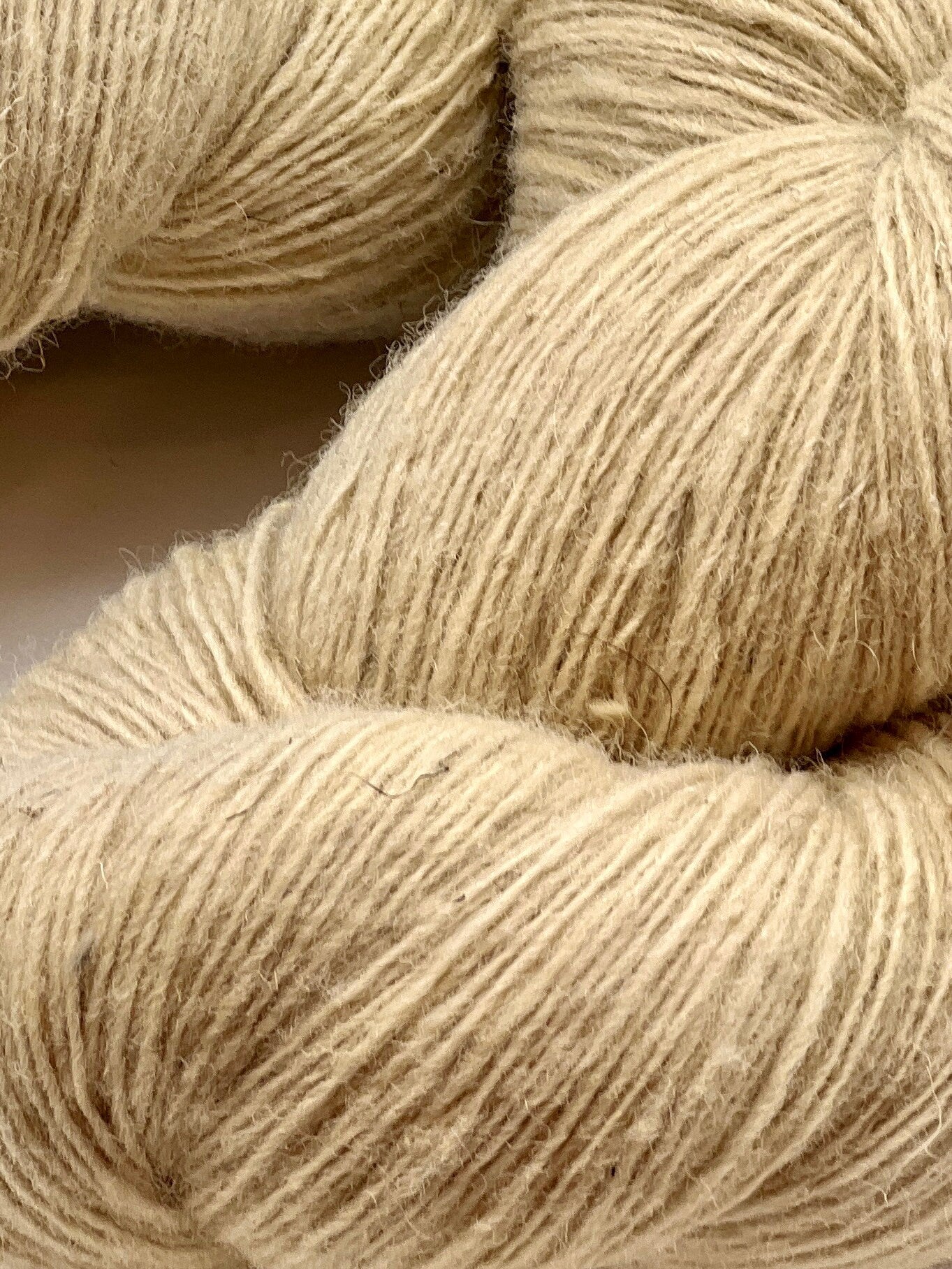 Close-up of beige yarn skeins on a neutral background