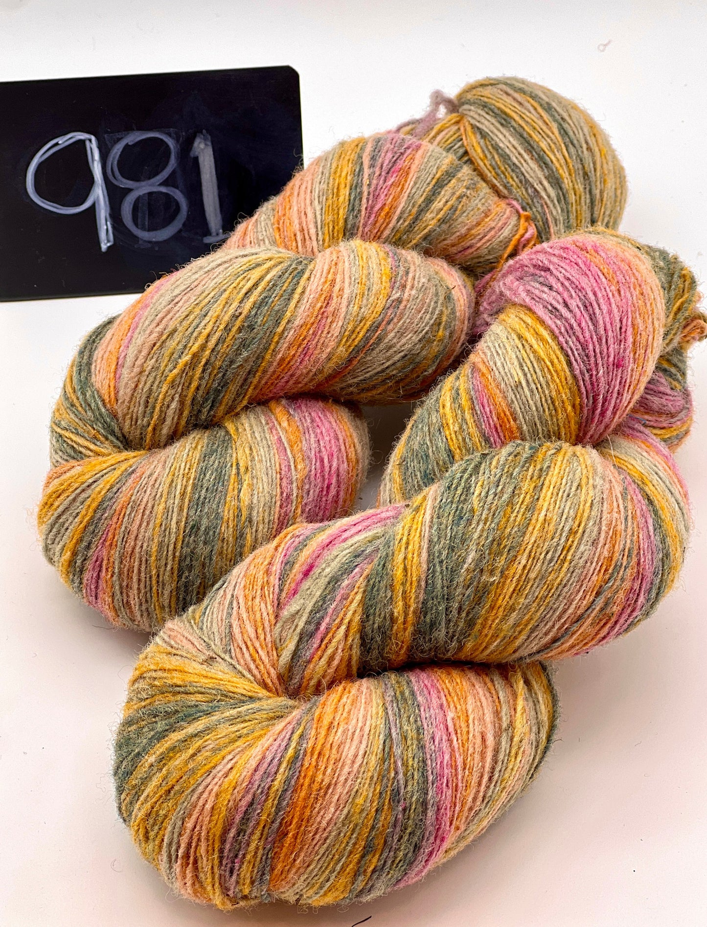 Multicolored yarn skeins on a white background with a label reading '981'.