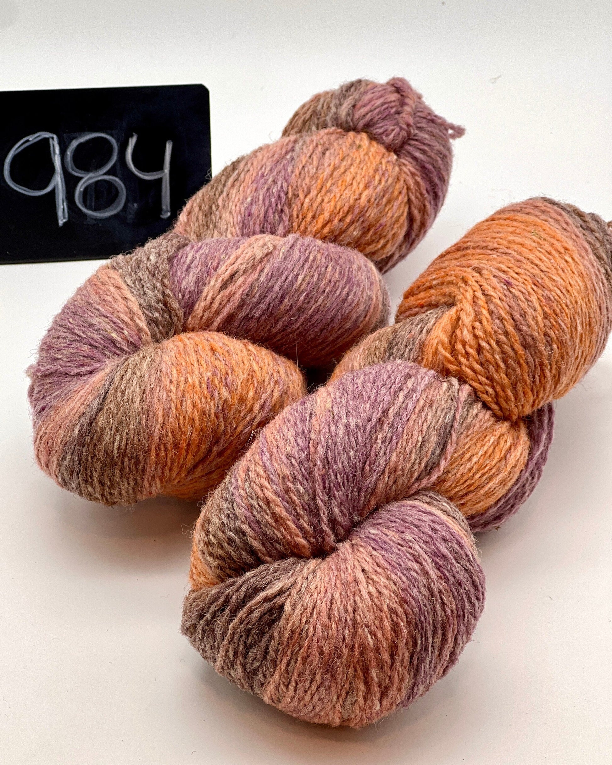 Three skeins of multicolored yarn on a white background with a label reading '984'.