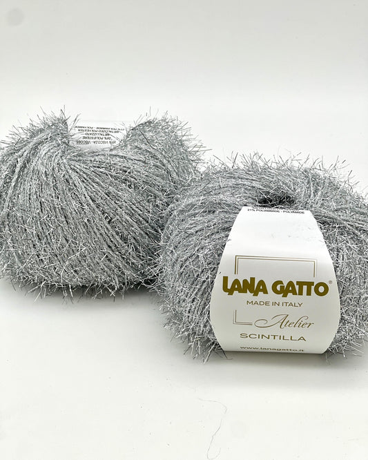 Two balls of gray yarn with a box labeled 'Lana Gatto' on a white background