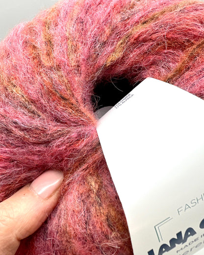 Ball of pink yarn with a label on a light gray background
