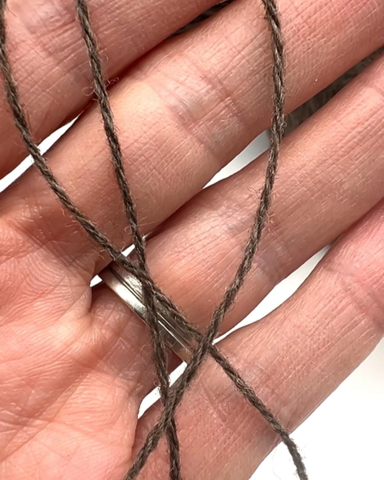 Close-up of a hand holding brown yarn
