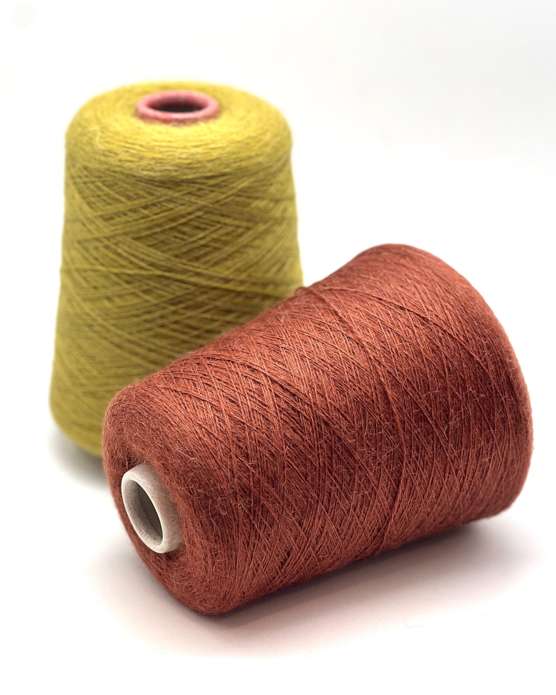 Two spools of yarn, one yellow and one brown, on a white background.