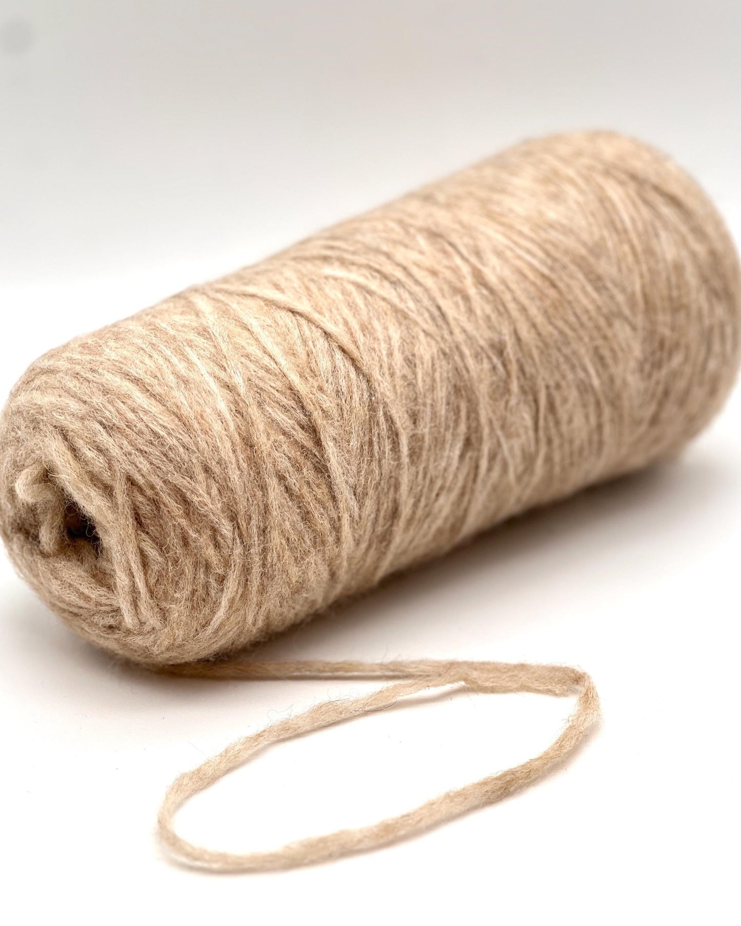 Roll of beige yarn on a white background