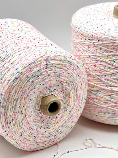 Two spools of multicolored yarn on a light gray background