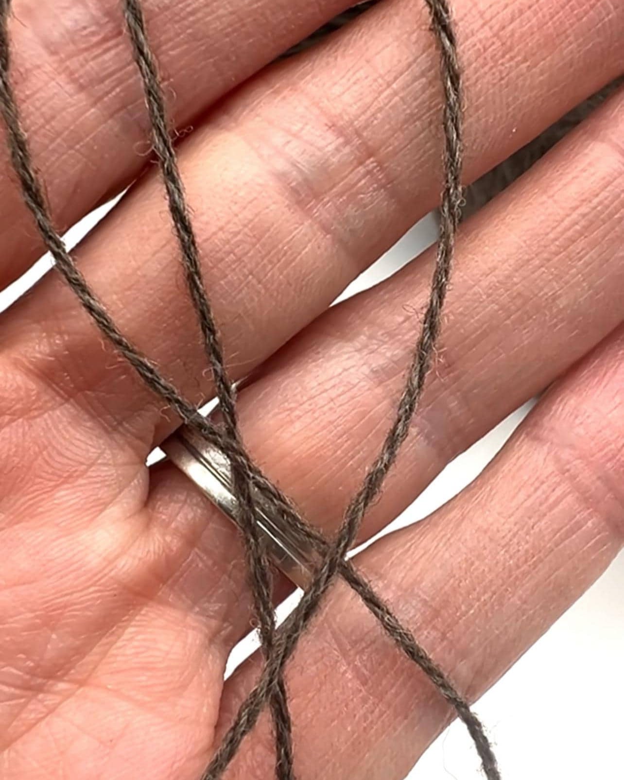 Close-up of a hand holding brown yarn