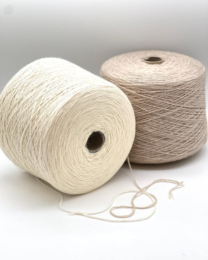 Two spools of yarn, one white and one beige, on a light background