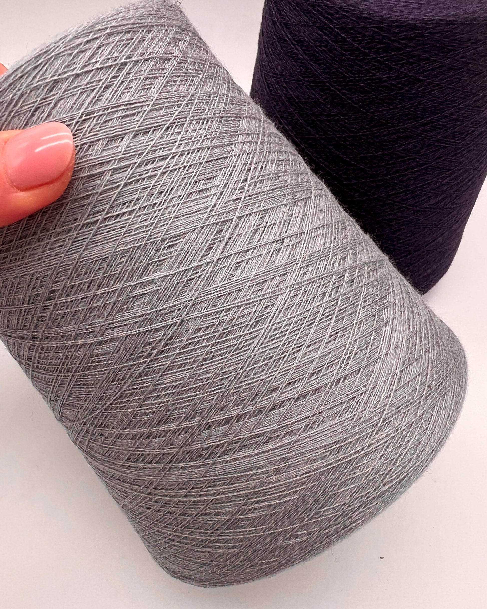 Gray yarn ball held by a hand on a white background