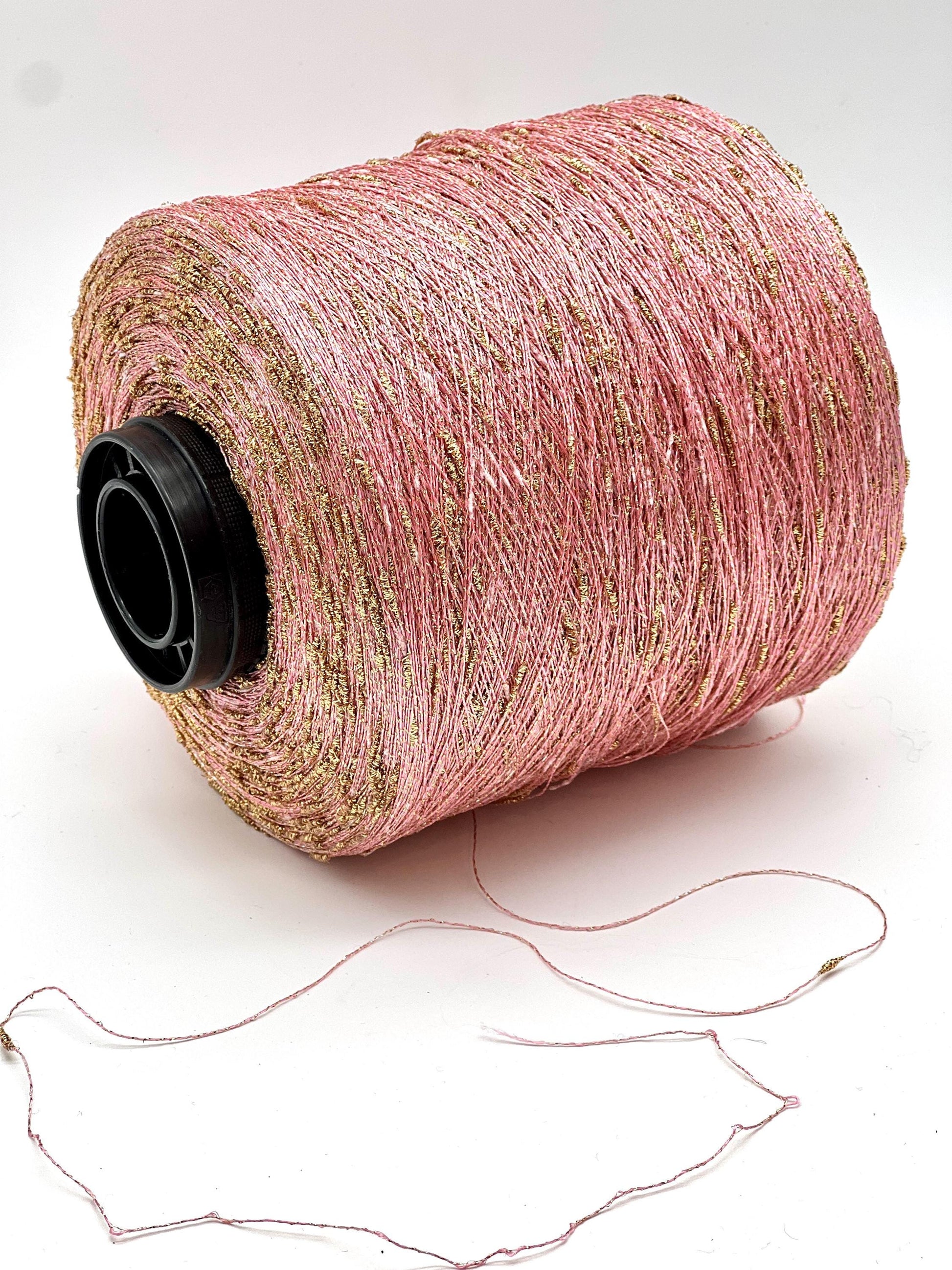 Spool of pink thread with gold flecks on a white background