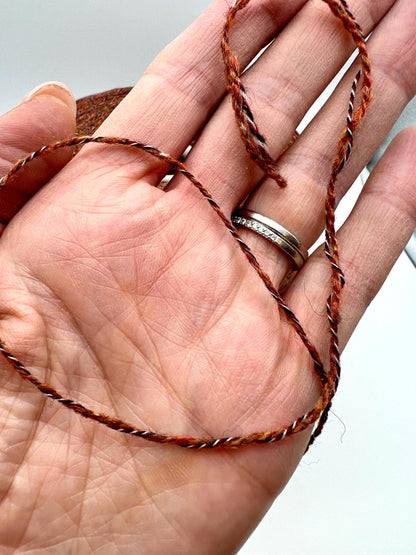 Hand holding a twisted brown string with a blurred background