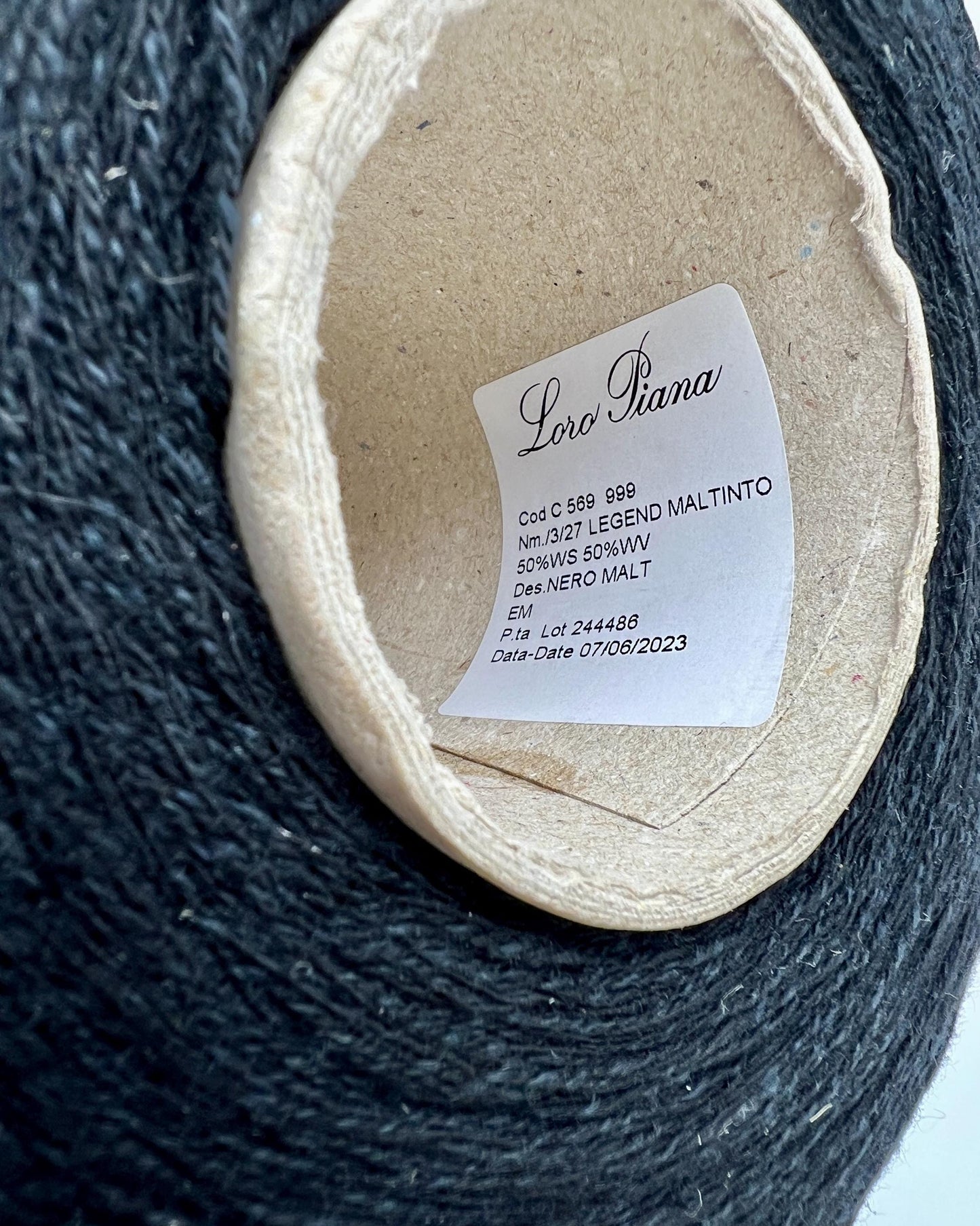 Close-up of a roll of black yarn with a label on a white background