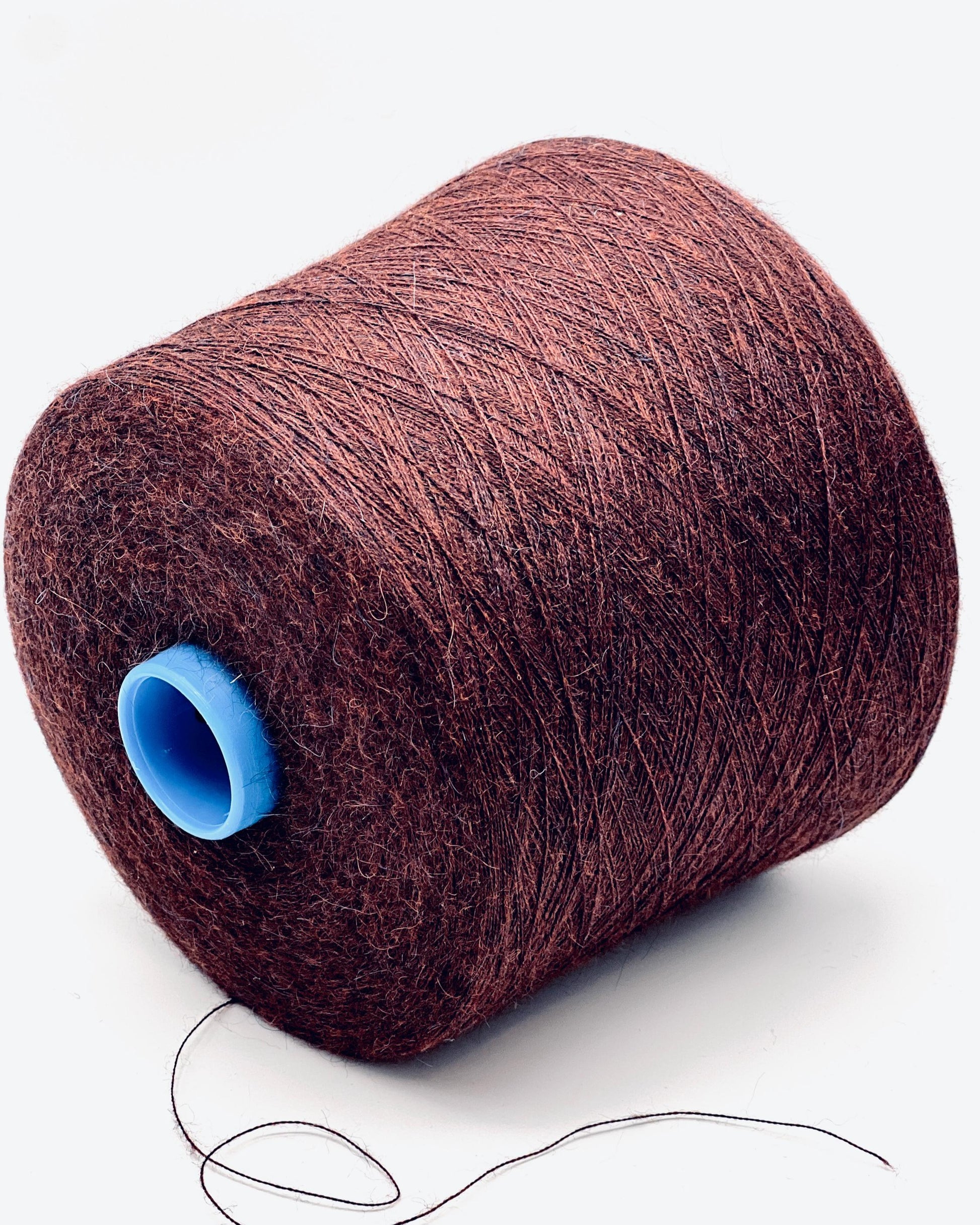 Spool of brown thread with a blue core on a white background