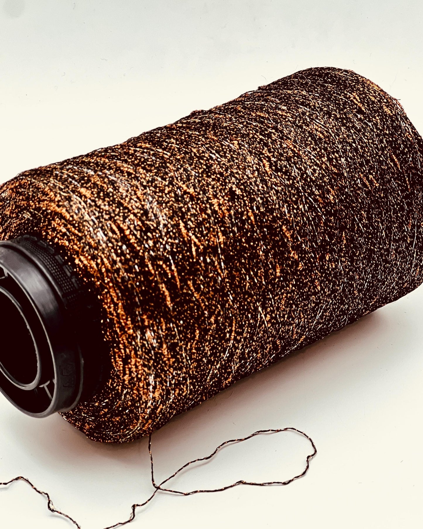 Roll of brown yarn with a black end on a light background