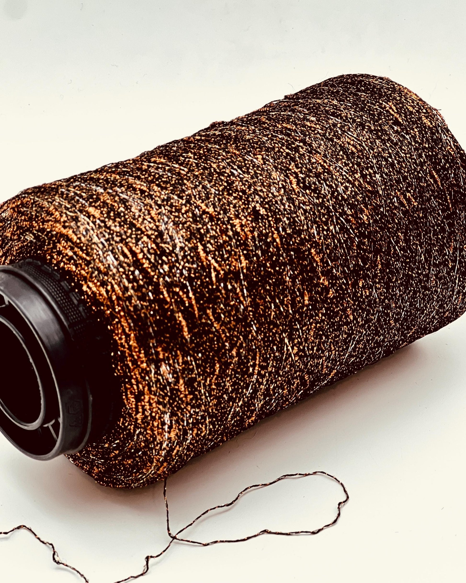 Roll of brown yarn with a black end on a light background