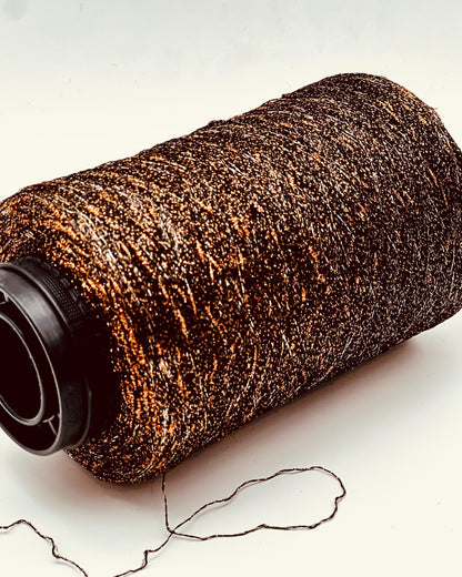 Roll of brown yarn with a black end on a light background