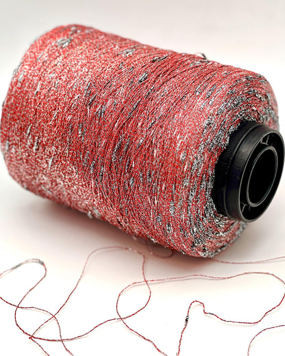 Spool of red thread with silver specks on a white background