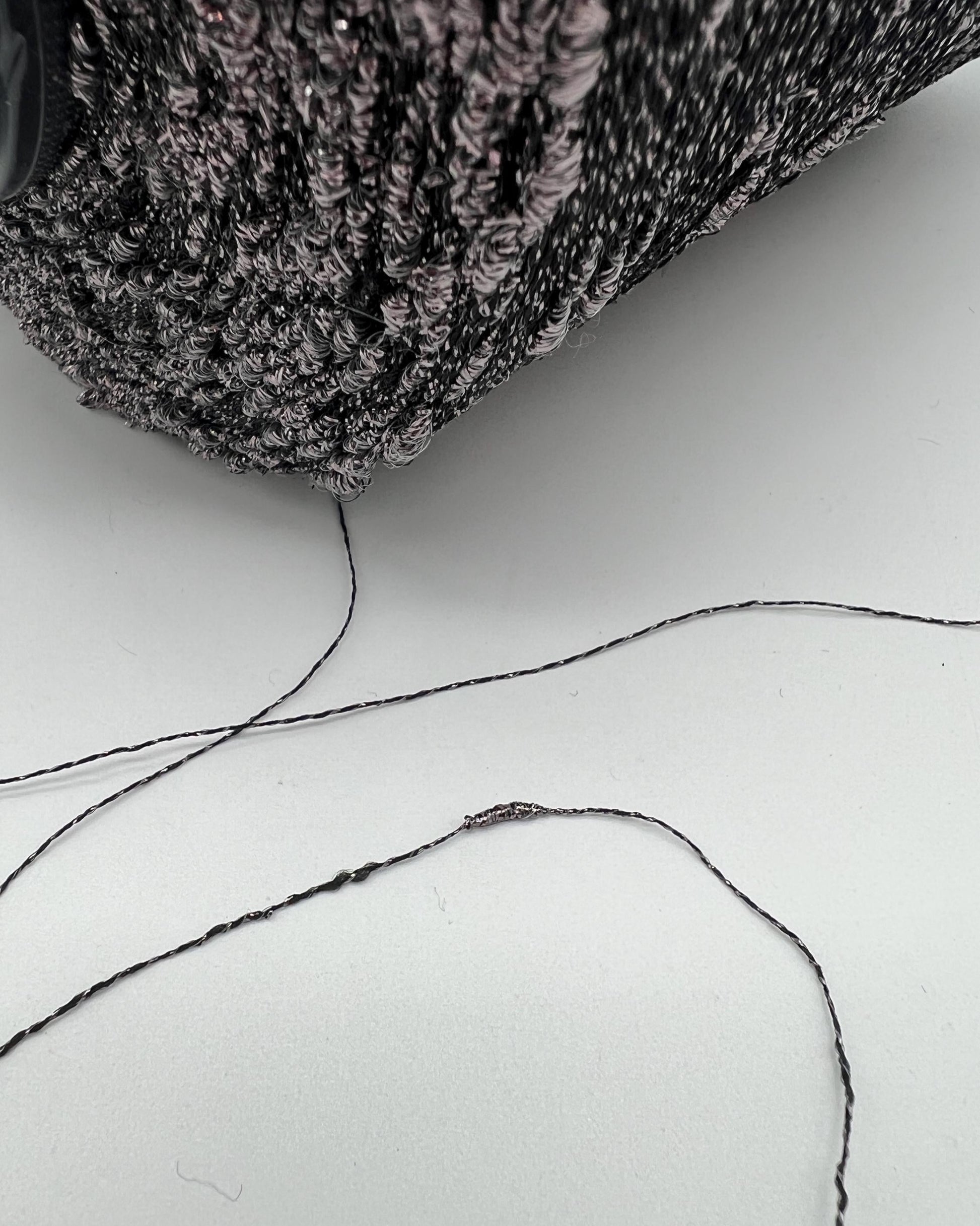 Close-up of a textured fabric surface with a piece of thread on a white background