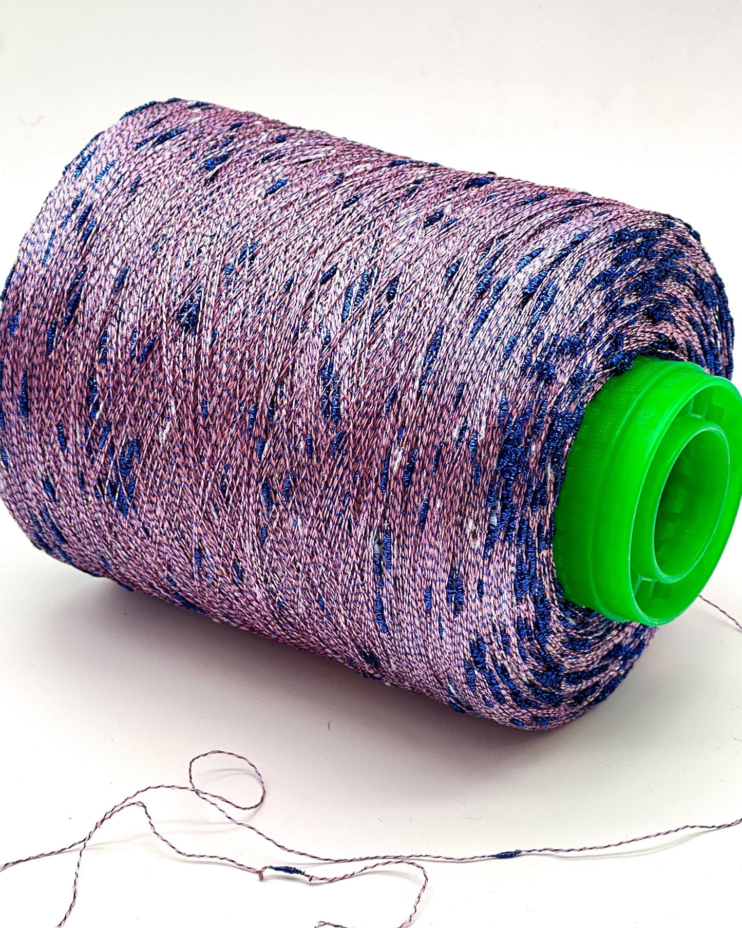 Spool of purple and blue thread with a green cap on a white background