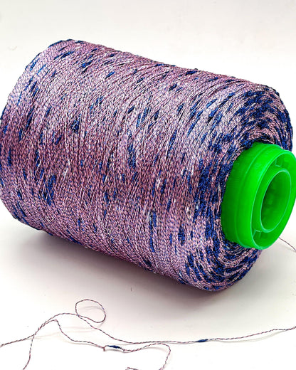 Spool of purple and blue thread with a green cap on a white background