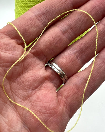 Silver ring on a hand with yellow thread and green yarn in the background