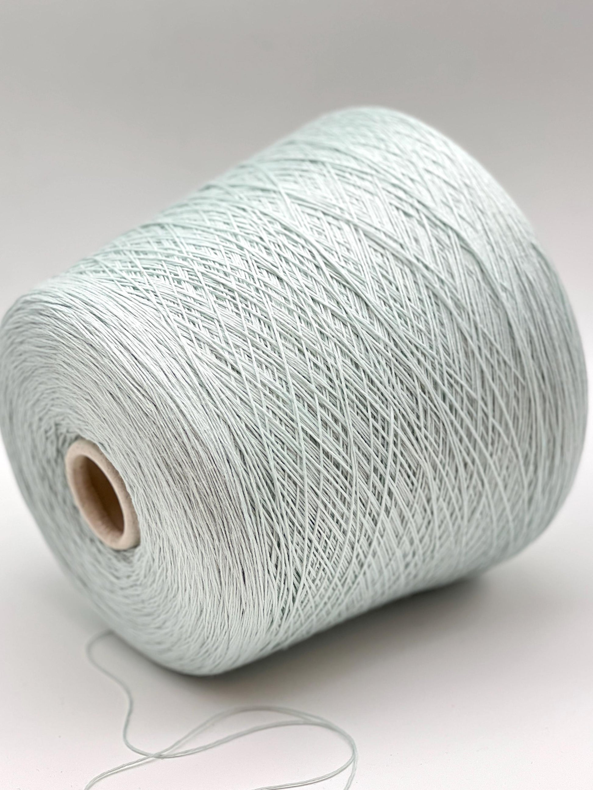 Spool of light blue yarn on a white background