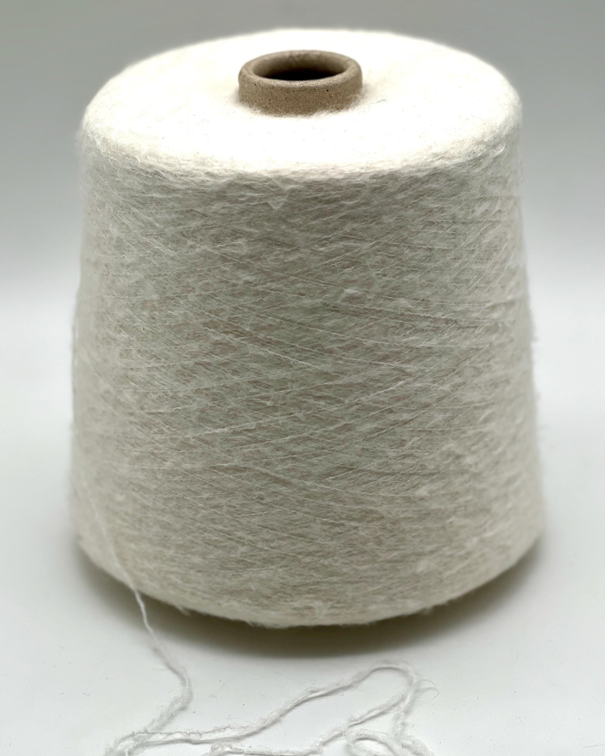 Spool of white yarn on a light gray background