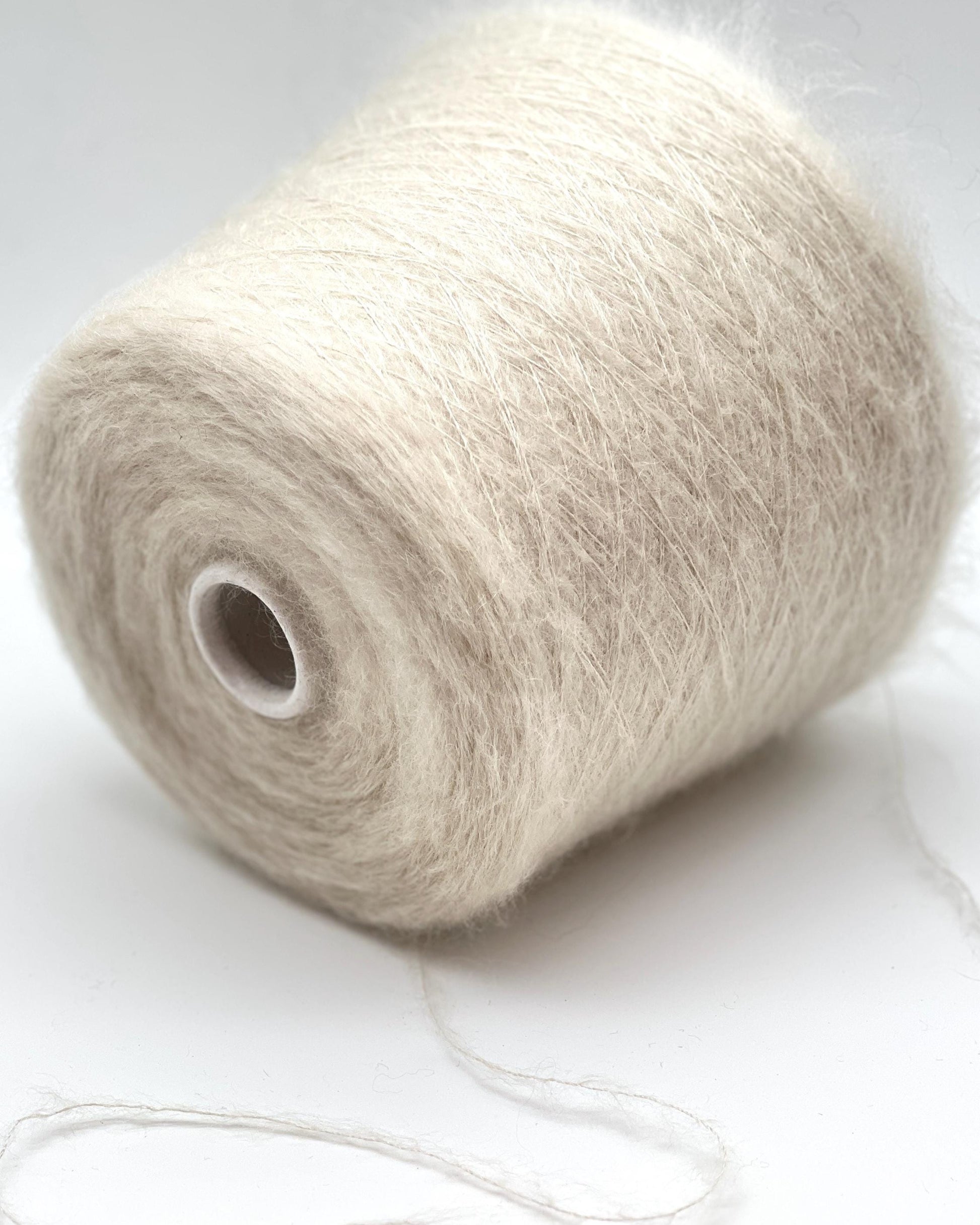 Spool of beige yarn on a white background