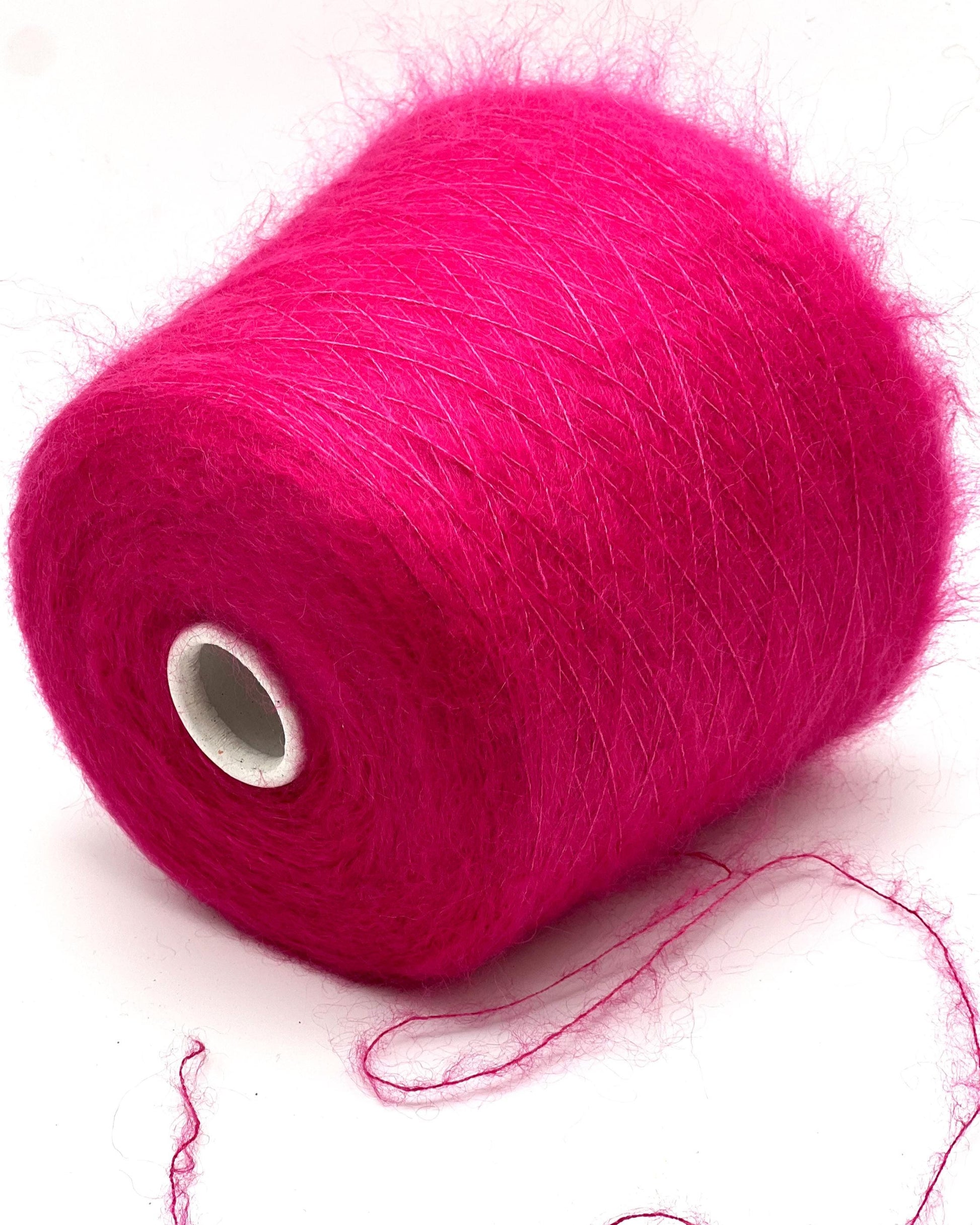 Spool of bright pink yarn on a white background