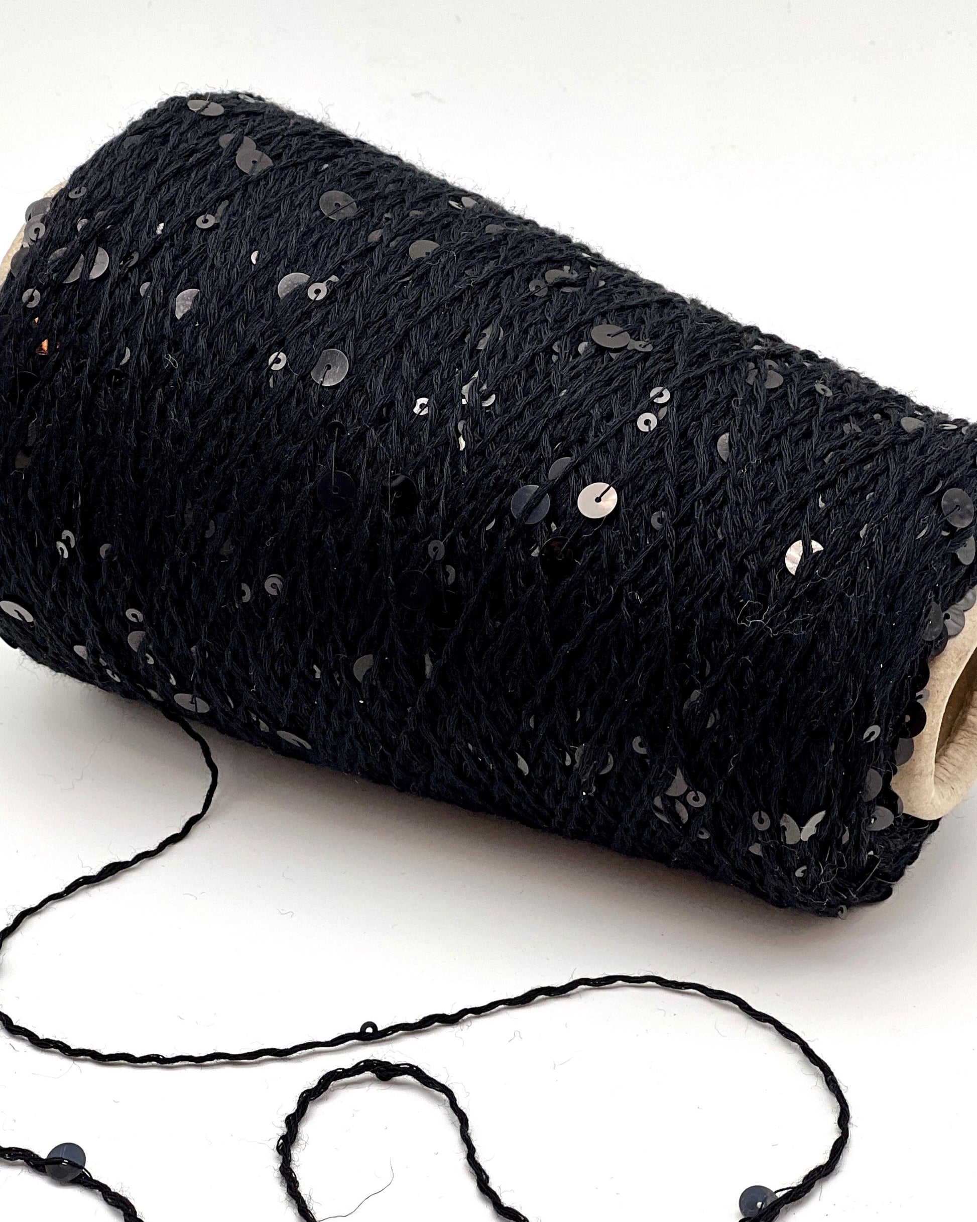 Roll of black yarn with sequins on a white background