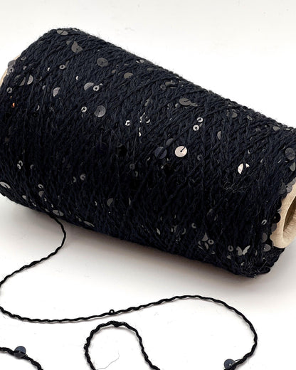 Roll of black yarn with sequins on a white background