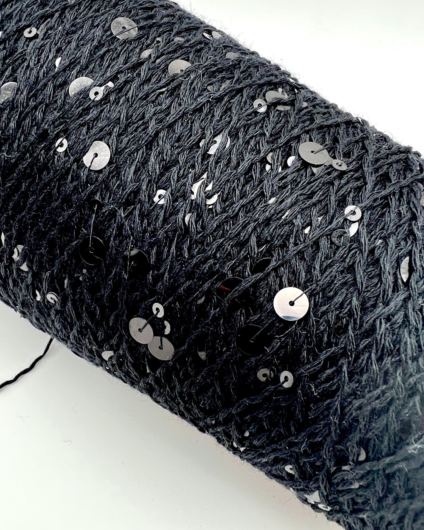 Black textured fabric with silver sequins on a white background