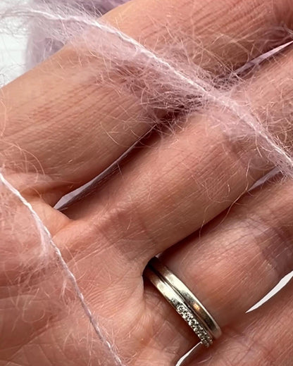 Gold ring with diamonds on a hand, wrapped in plastic.