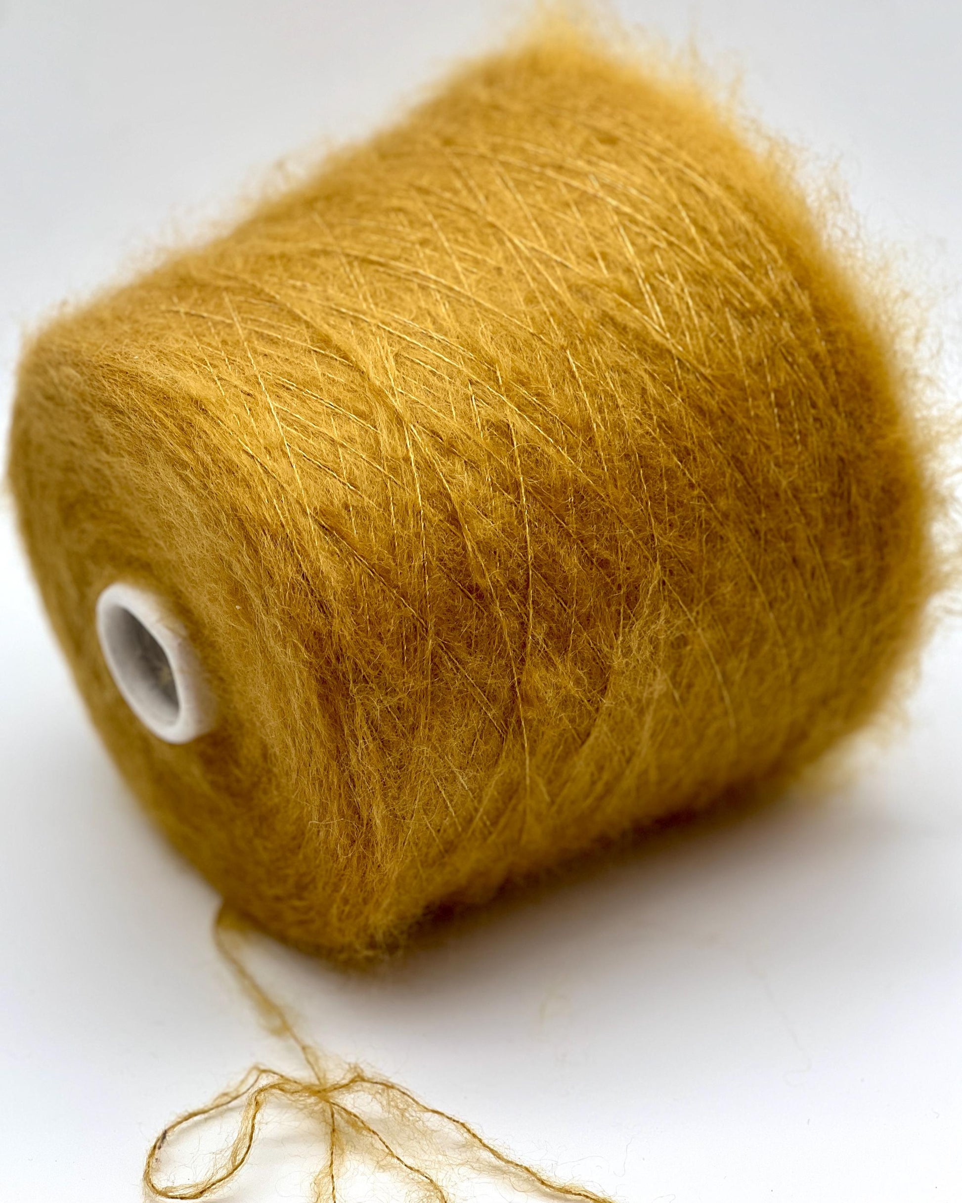 Spool of mustard yellow yarn on a white background