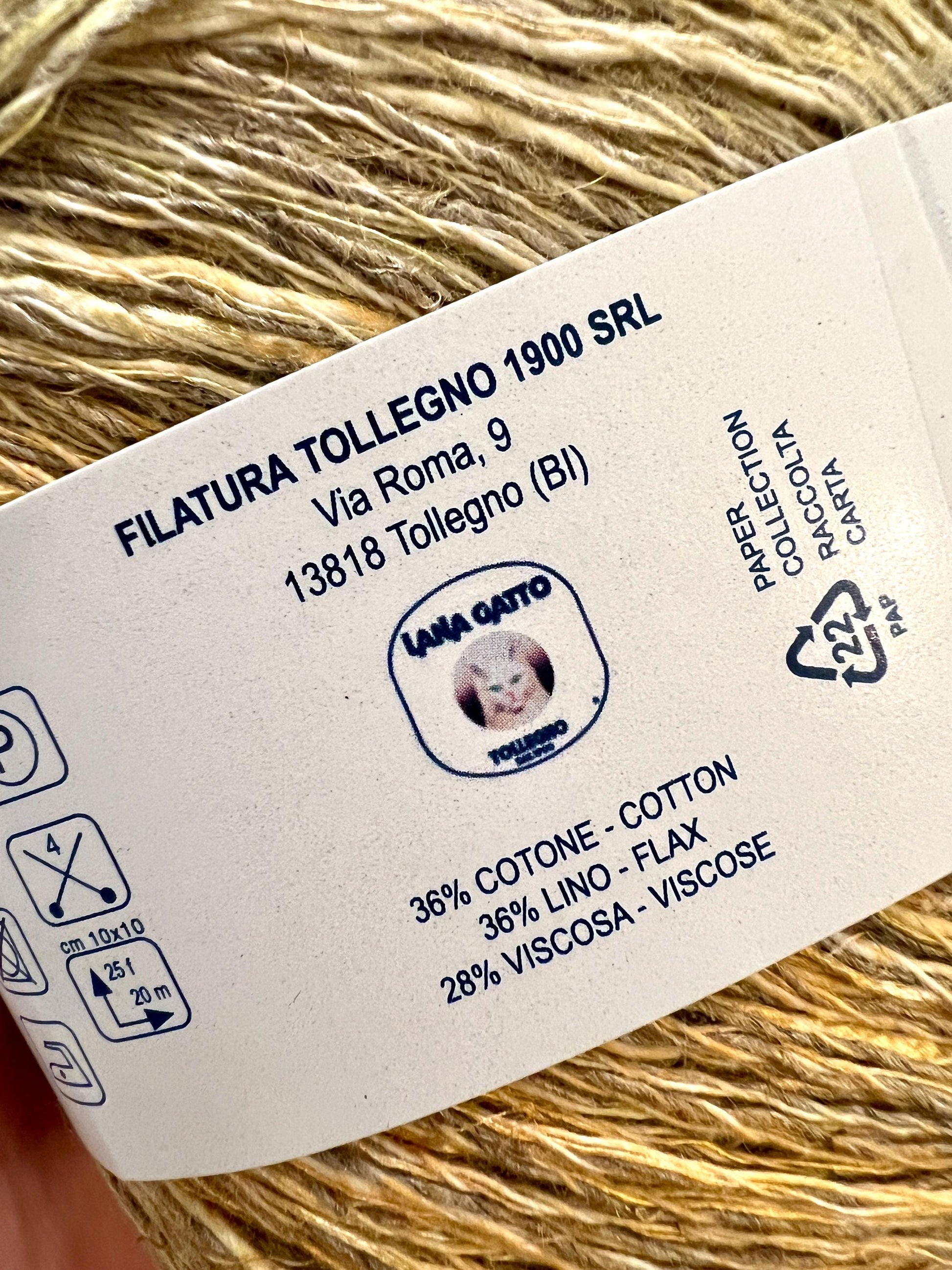 Yarn ball with a label showing Filatura Tollegno 1900 SRL details and Lana Gatto branding.