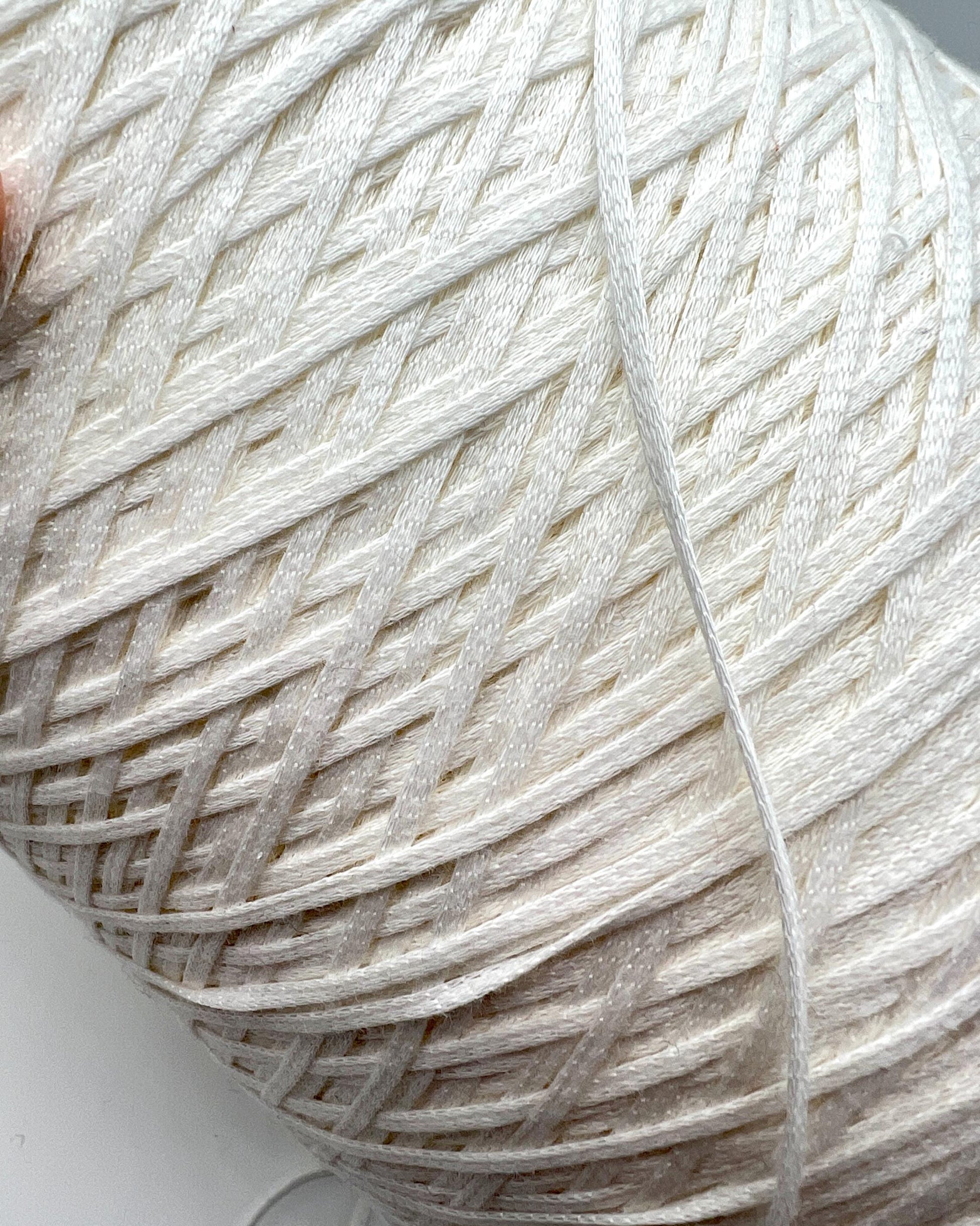 Close-up of a ball of white yarn on a light background