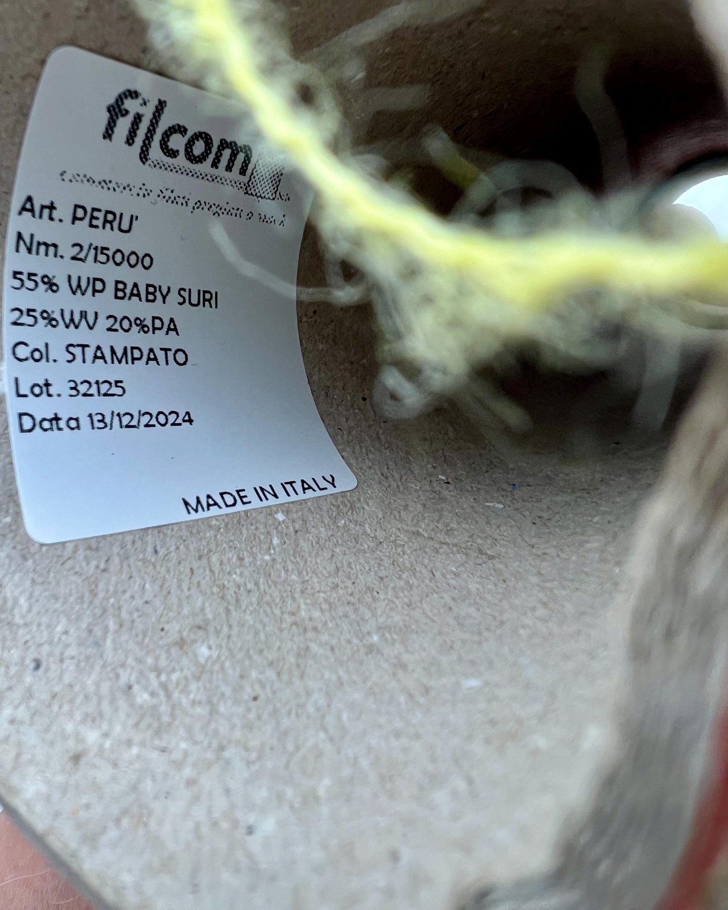 Close-up of a label on yarn with 'filcom' branding and product details.