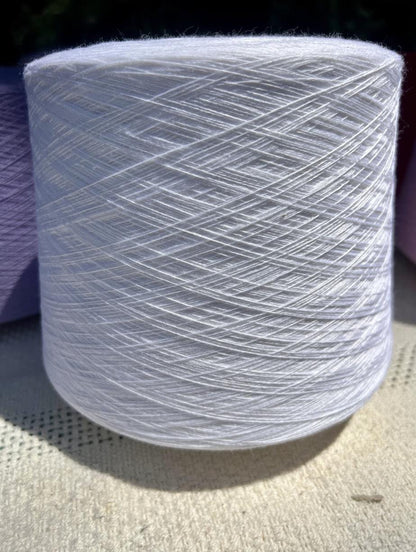 Spool of white yarn on a textured surface