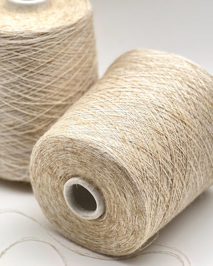 Two spools of beige yarn on a light gray background