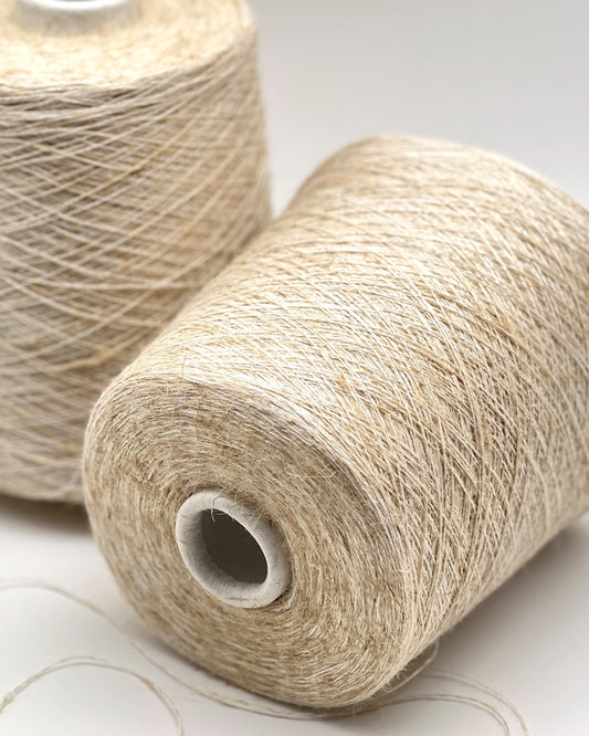 Two spools of beige yarn on a light gray background