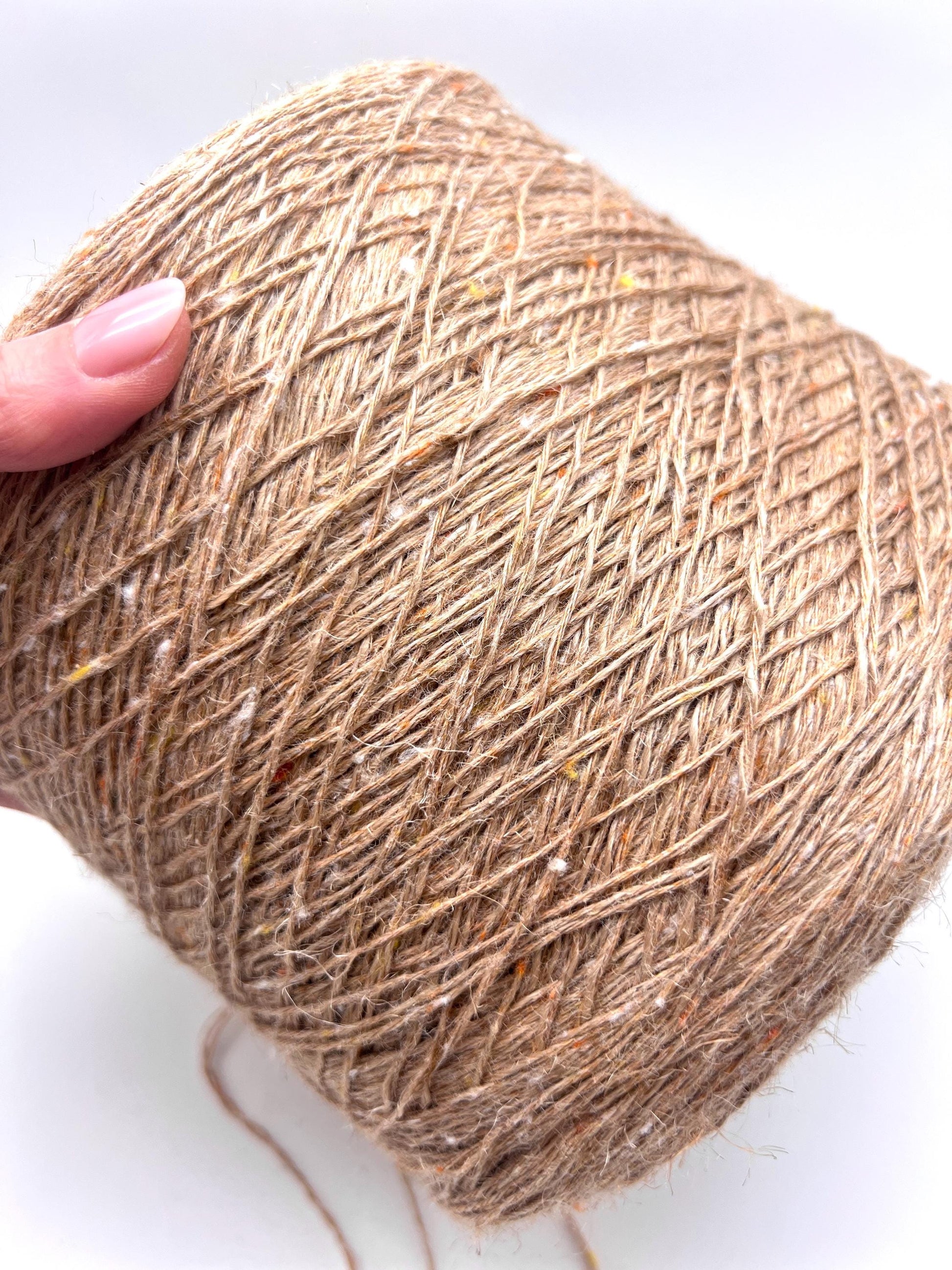 Ball of brown yarn held by a hand on a white background