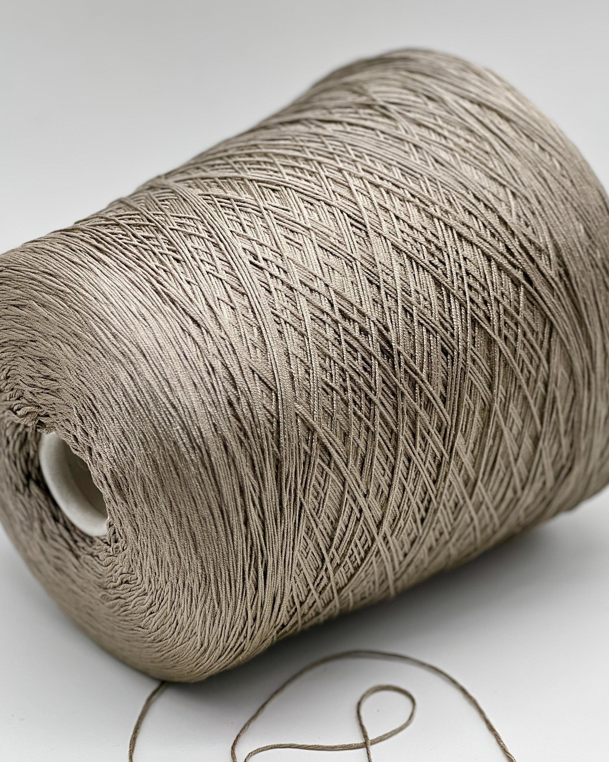 Close-up of a roll of beige thread on a white background