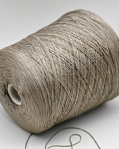 Close-up of a roll of beige thread on a white background