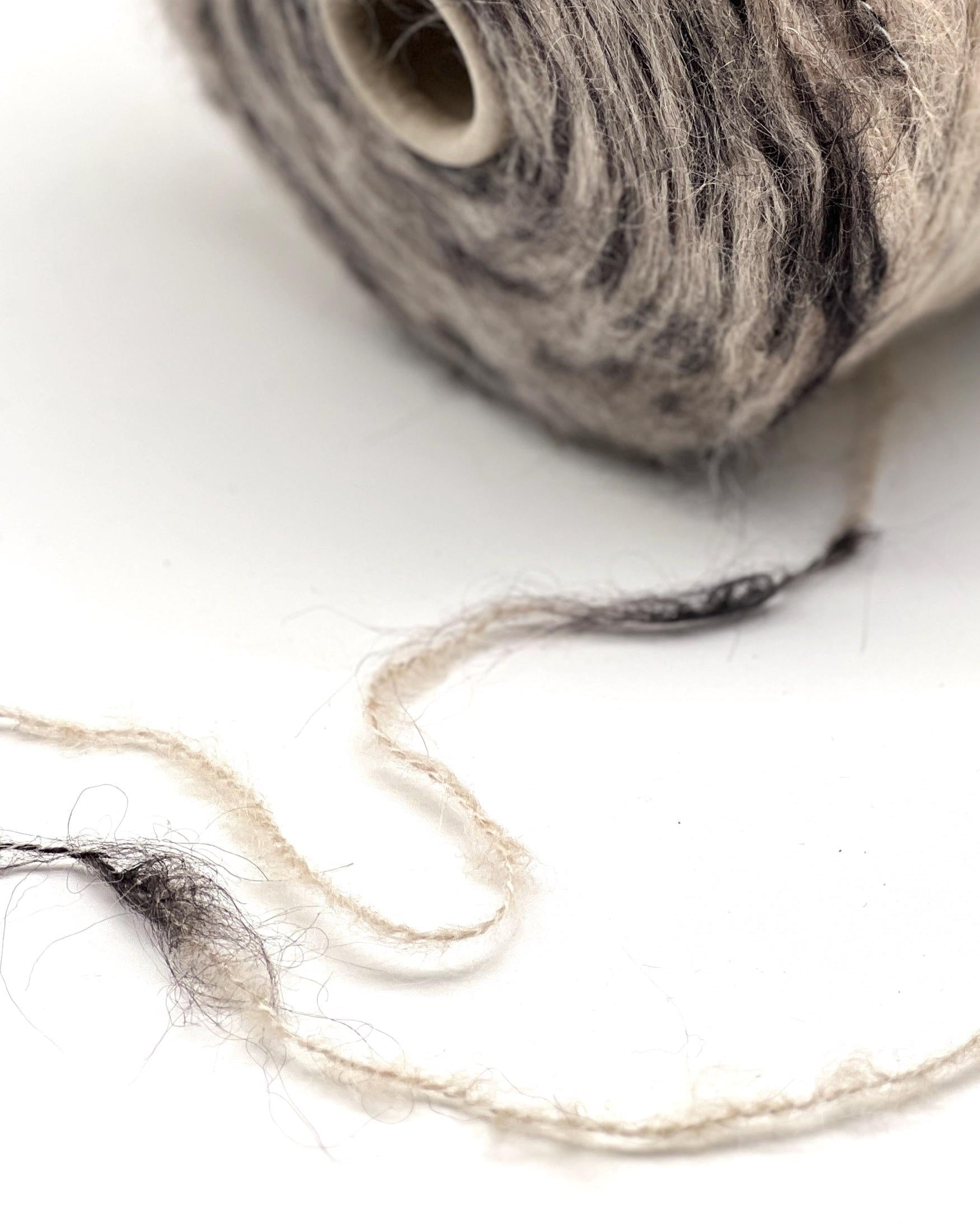 Ball of gray yarn with a few strands on a white background