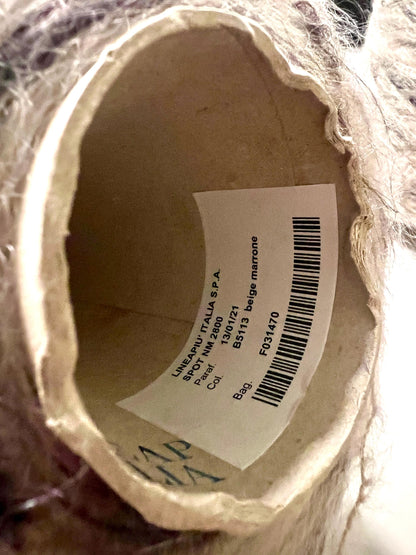 Close-up of a label inside a yarn ball with text and a barcode.