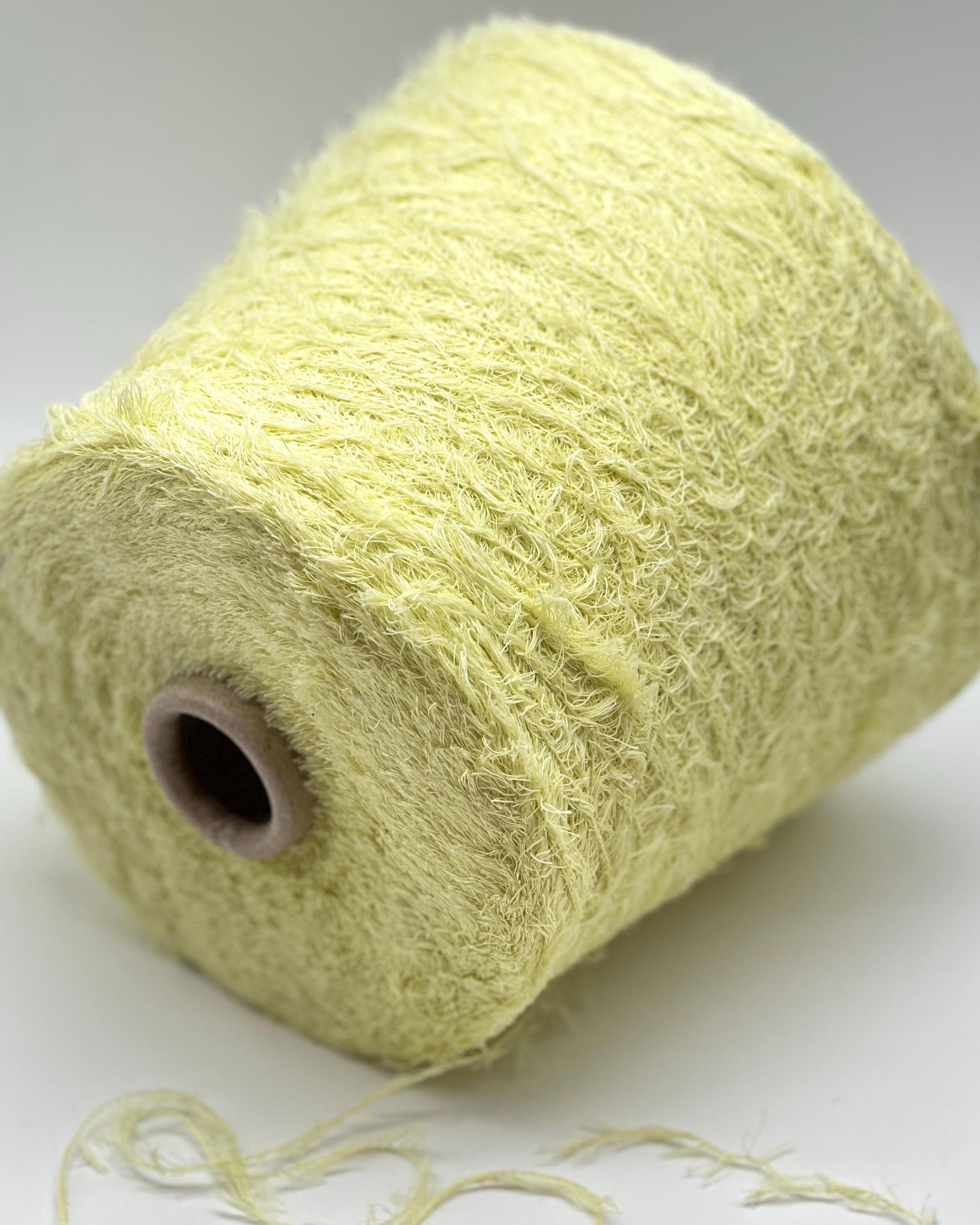 Spool of light green yarn on a white background
