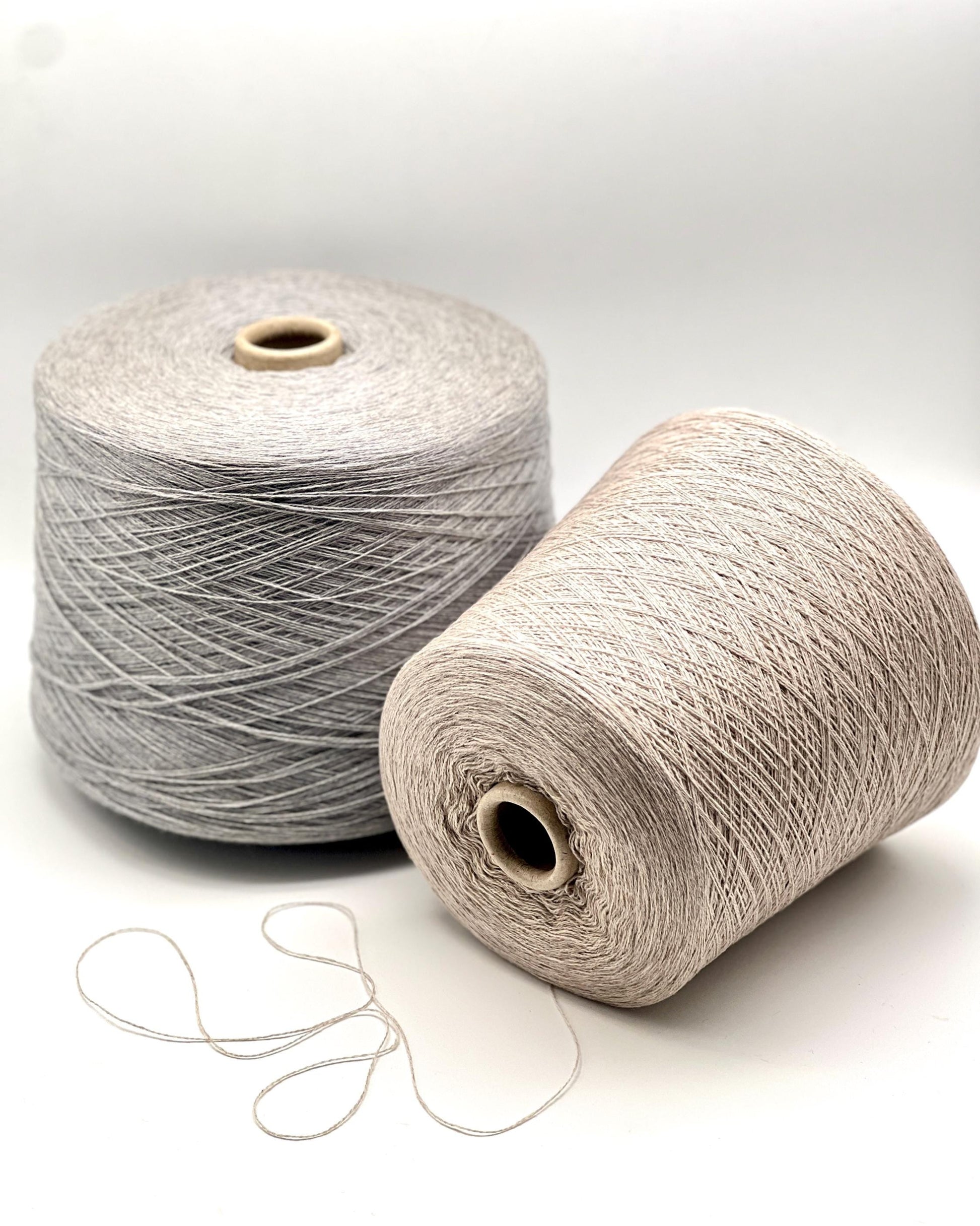 Two spools of yarn, one gray and one beige, on a white background.