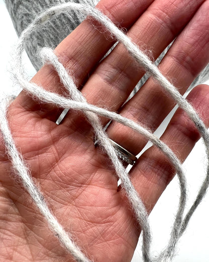 White yarn wrapped around a hand with a white background