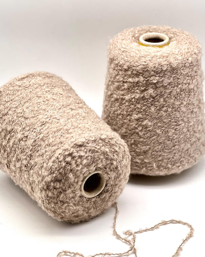Two beige yarn cones on a white background