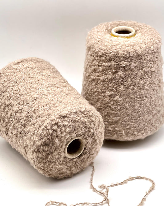 Two beige yarn cones on a white background